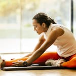 A woman enjoying a yoga stretch indoors, promoting a healthy lifestyle.