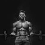 Black and white portrait of a muscular man lifting weights, showcasing strength and fitness.